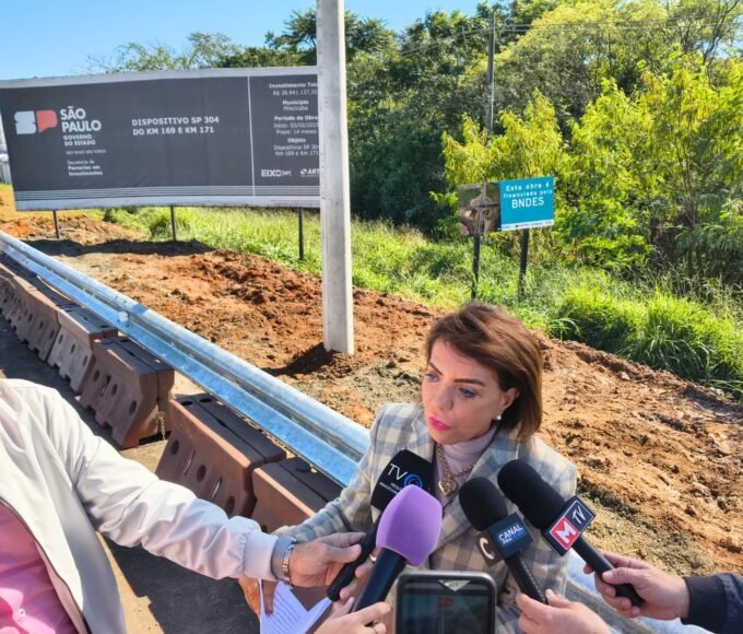 Deputada Bebel fiscaliza obras na SP-304 e cobra crédito ao BNDES, que fez o financiamento 14 18 06 26 A deputada Professora Bebel fala com a imprensa tendo as placas de divulgacao ao fundo